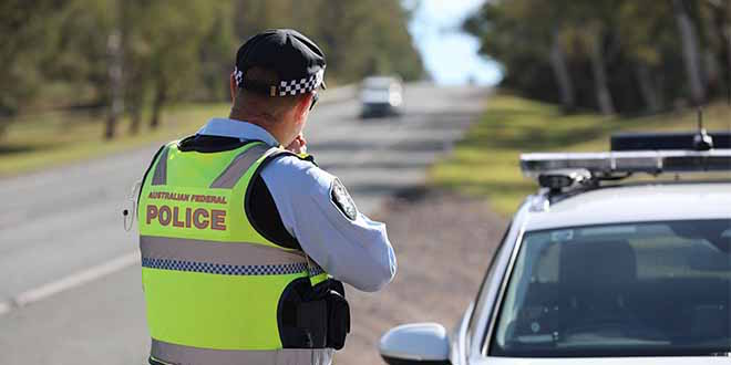 An Australian Federal Police officer checks the speed of motorists