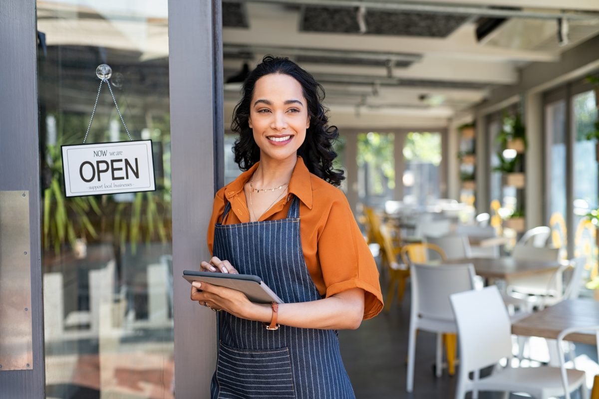 happy waitress standing at restaurant entrance