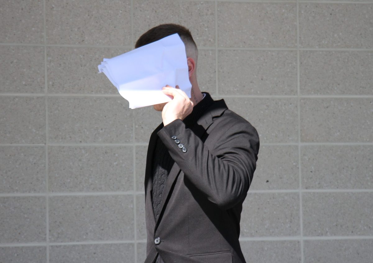 man leaving court hiding face behind piece of paper