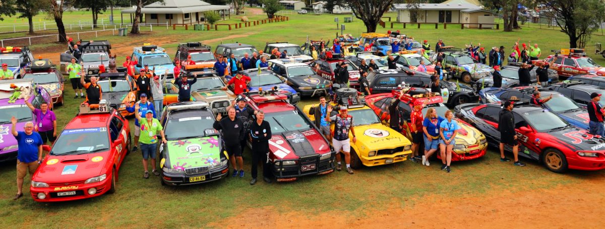 Colourful cars and people parked on an oval during the esCarpade event for Camp Quality