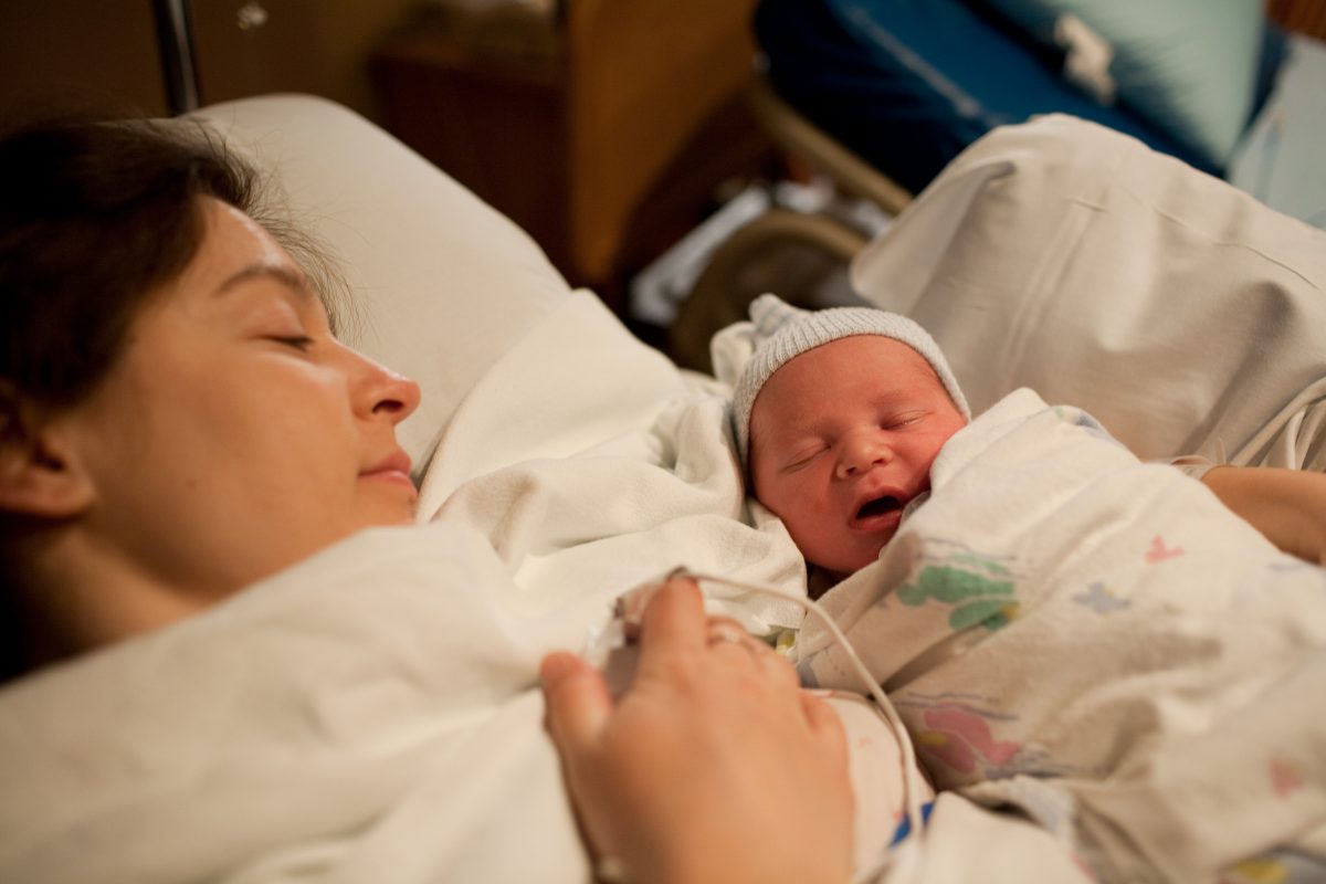 Mother holding newborn baby boy in hospital bed
