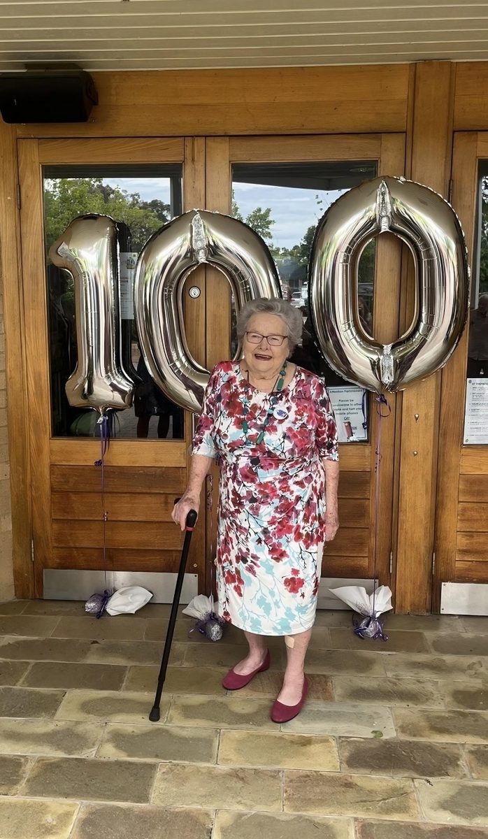 Joan Plunkett in front of 100 balloons