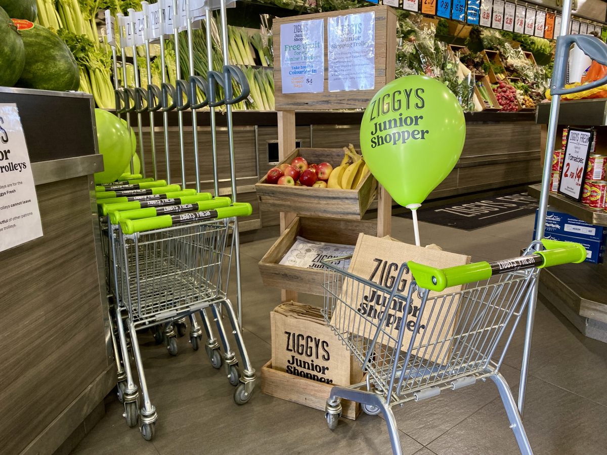 Child sized trolleys, balloons, shopping bags, colouring in books and fruit on a stand with Ziggy's Fresh branding.