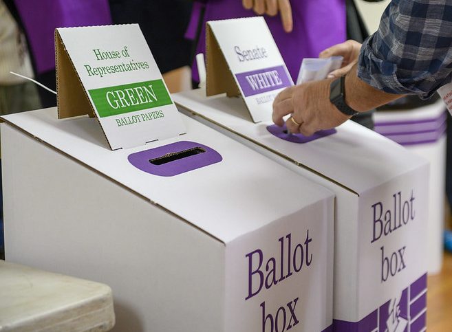 Ballot boxes and someone casting a vote