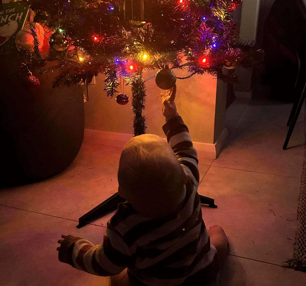 Baby Henry reaching for bauble on Christmas tree.