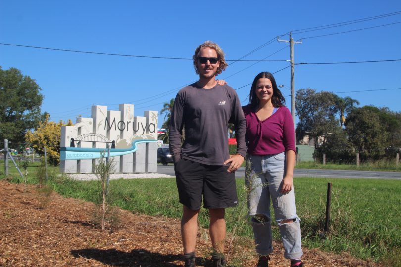 Alex Chiswell and Eliza Cannon standing in front of Moruya town sign.