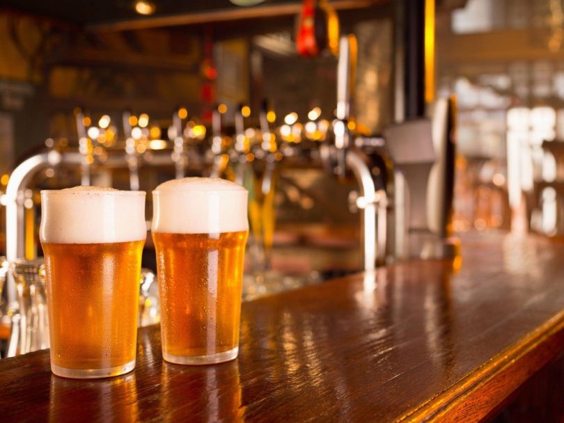 Two pints of beer sitting on bar