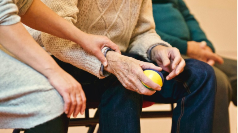 Hands of an aged care resident holding ball.