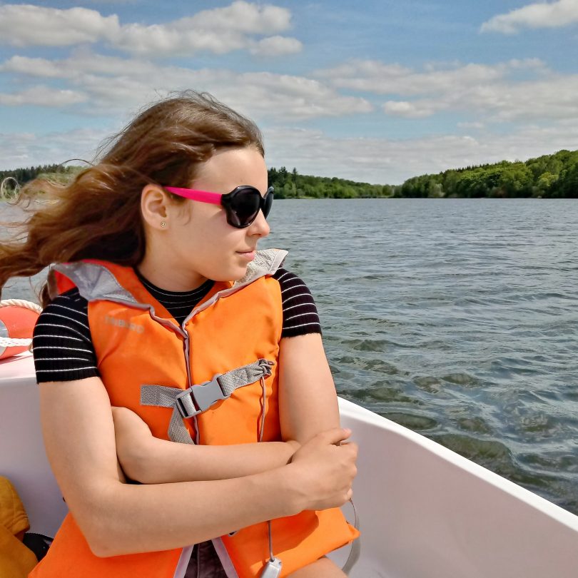 Young girl wearing a lifejacket and sunglasses on a boat.