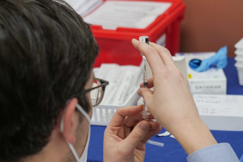 Doctor holding COVID-19 vaccination needle.