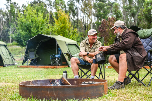 Two male campers around a fire