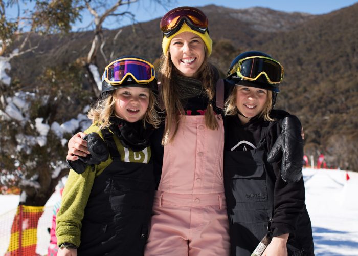 Torah Bright hugging two children at ski field