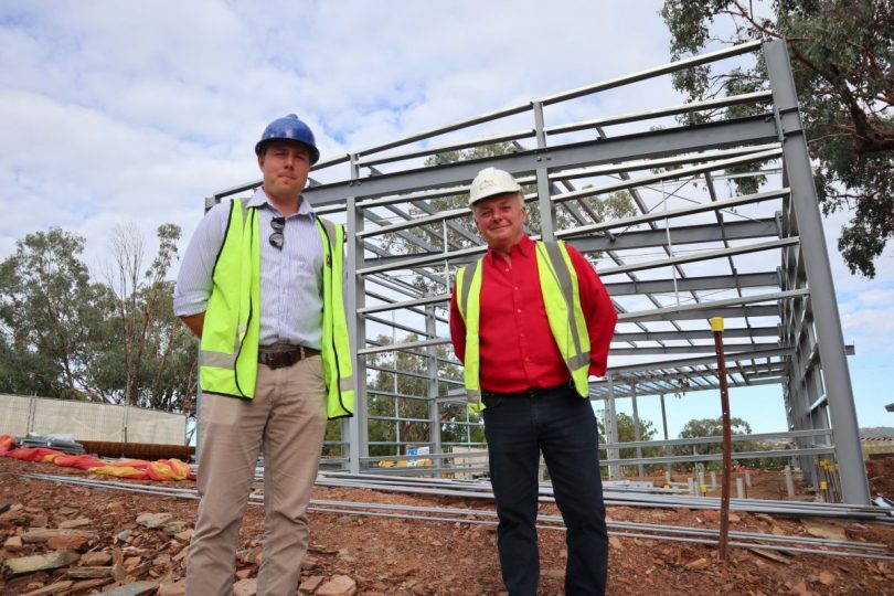 Two men standing in front of a metal structure