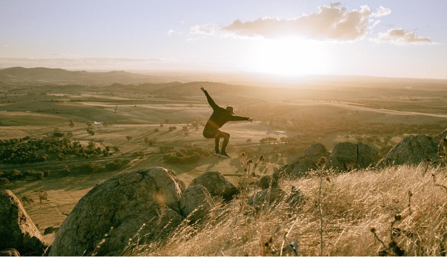 Person jumping at the top of a mountain