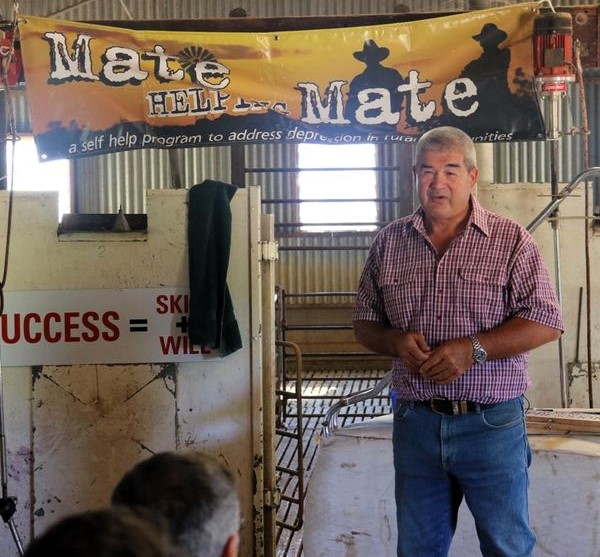Man addressing a group of farmers in a woolshed