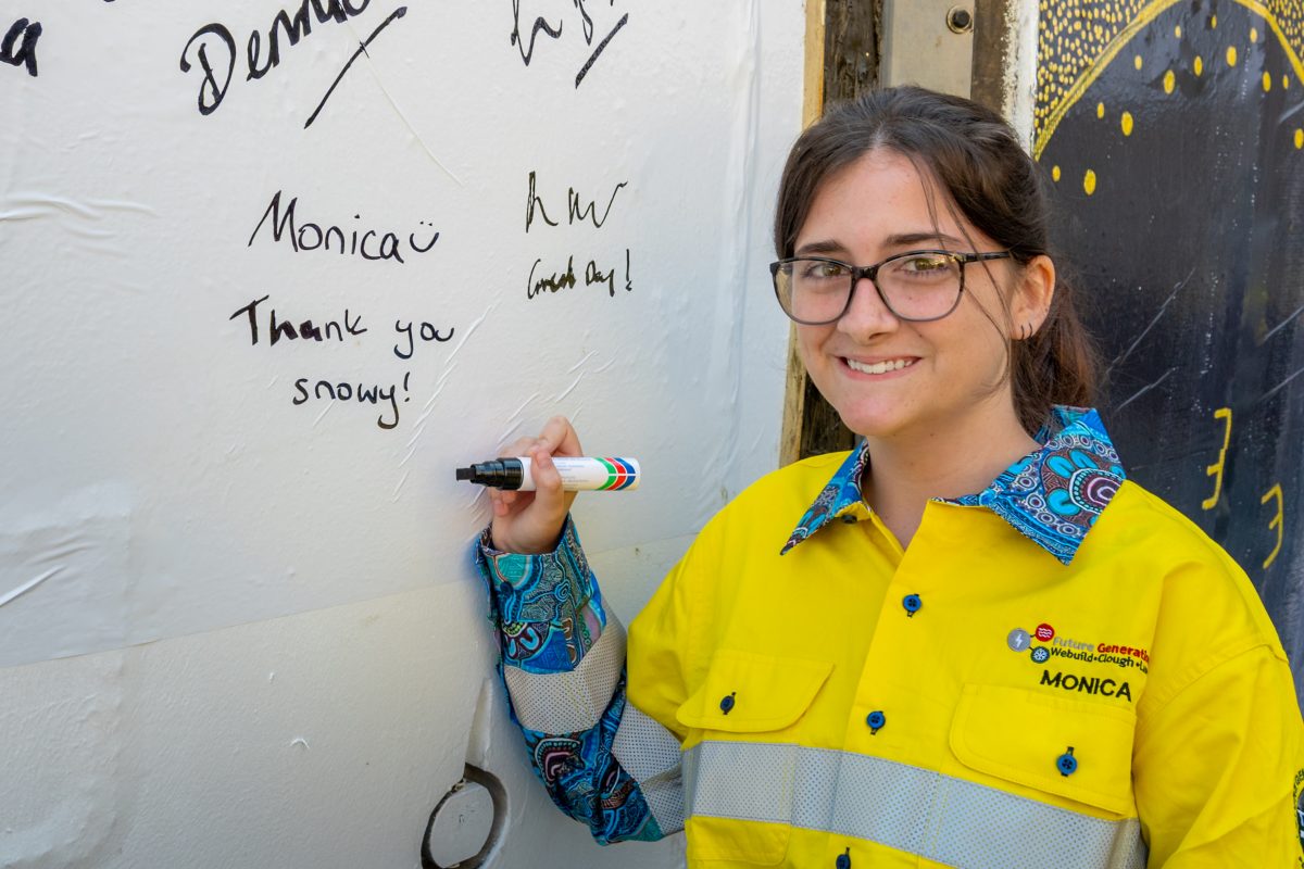 A smiling woman in a yellow high-vis shirt standing next to a TBM 