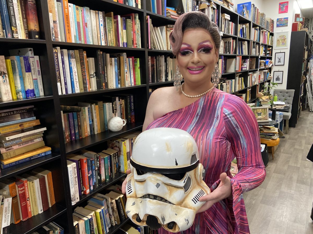 Drag queen holding a star wars helmet in a book store