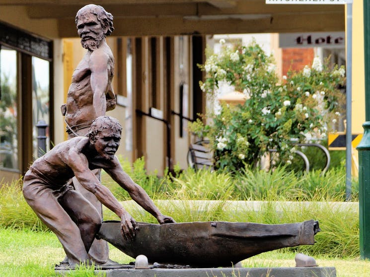 Statues depicting Aboriginal people, one dragging a boat