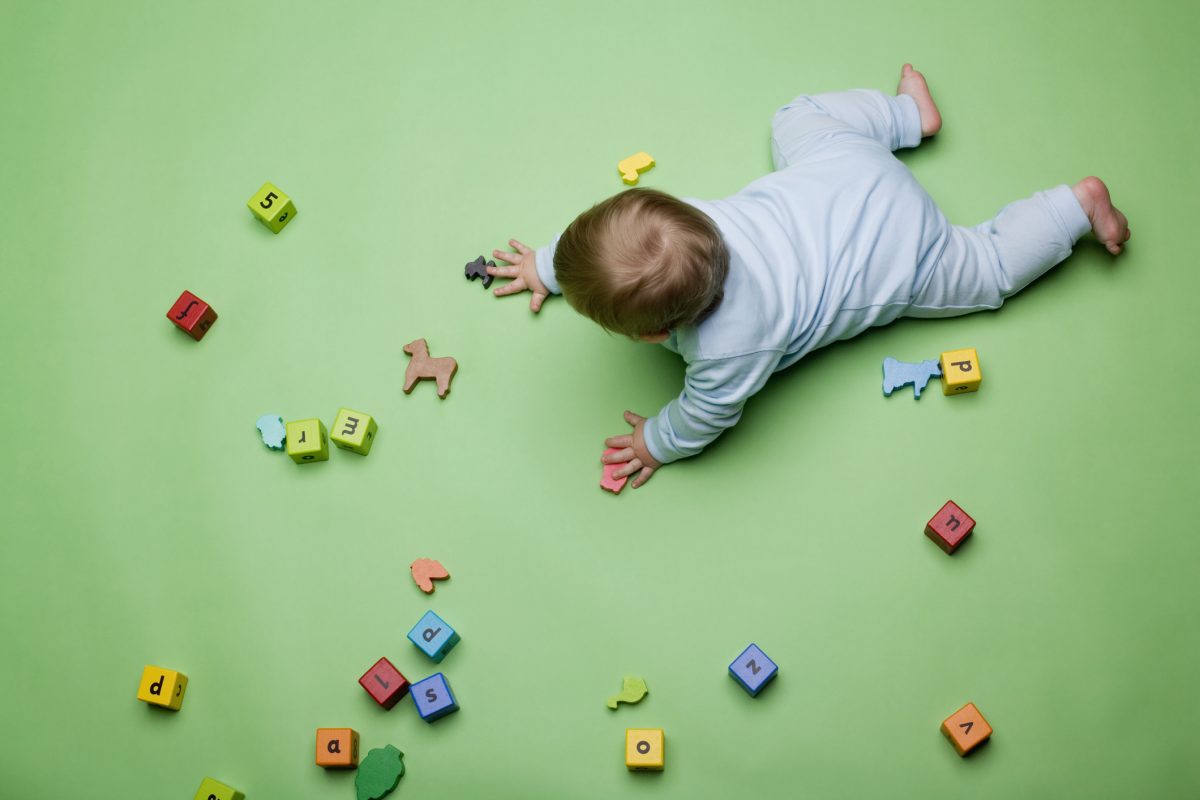 baby crawling surrounded by lettered blocks