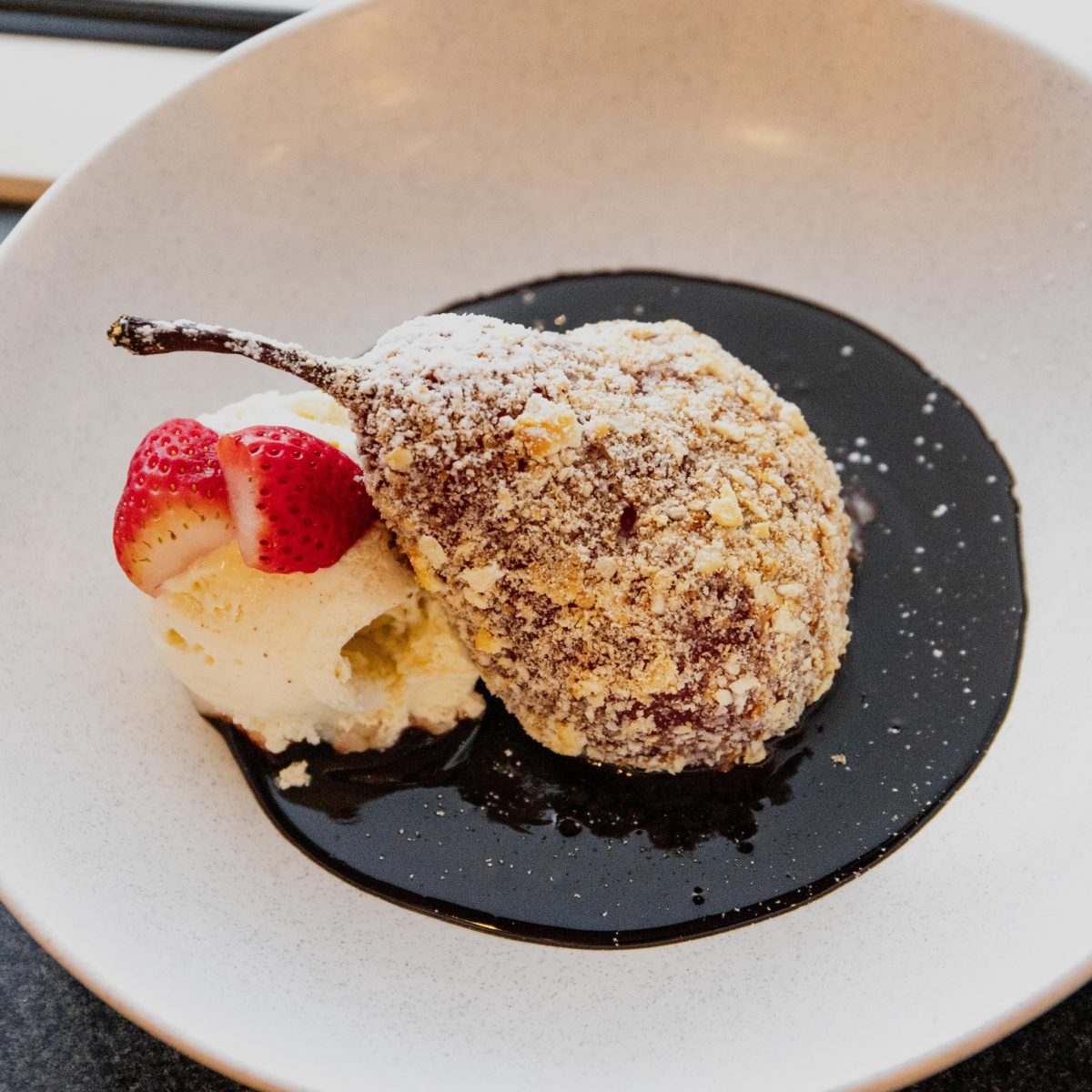 The poached pear is coated with a buttery crumb, which provides great contrast to the smooth icecream and hot fudge sauce. Photo: Supplied.