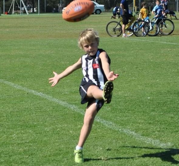 young boy kicks football 