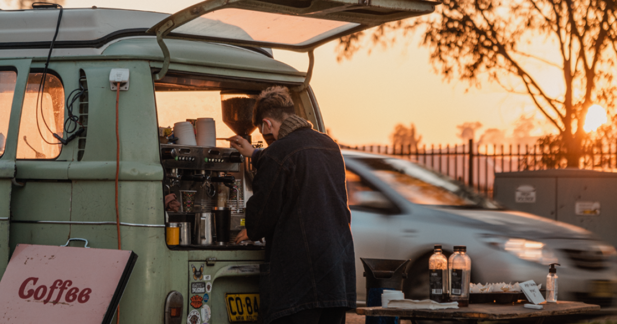 Woman working a coffee machine in the back of a combi van