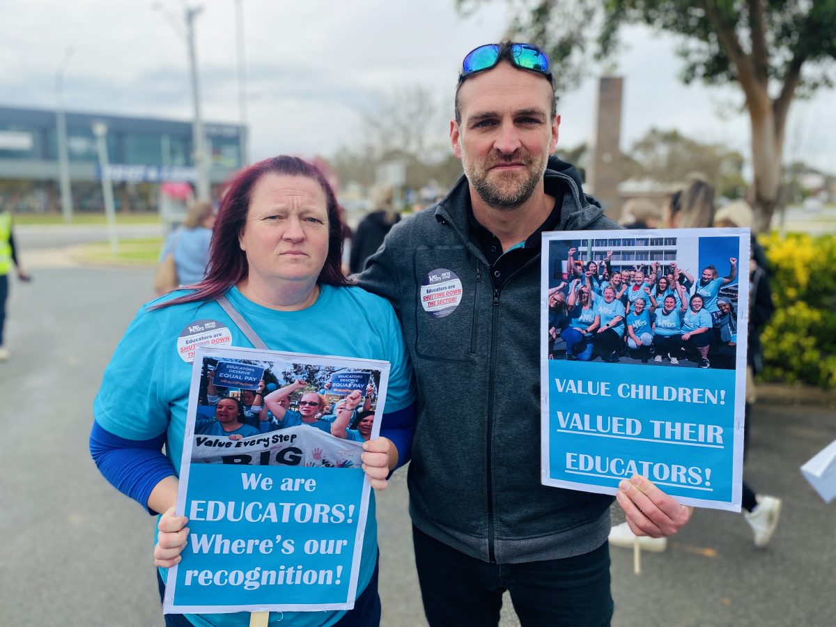 Suellen Roberts and Christian Callinan hold protest signs