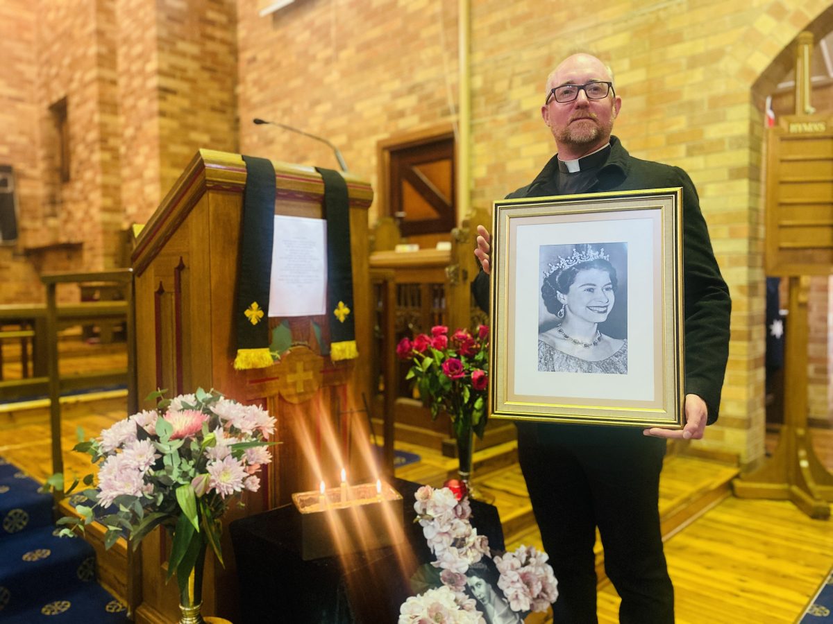 Priest holding Queen's portrait 