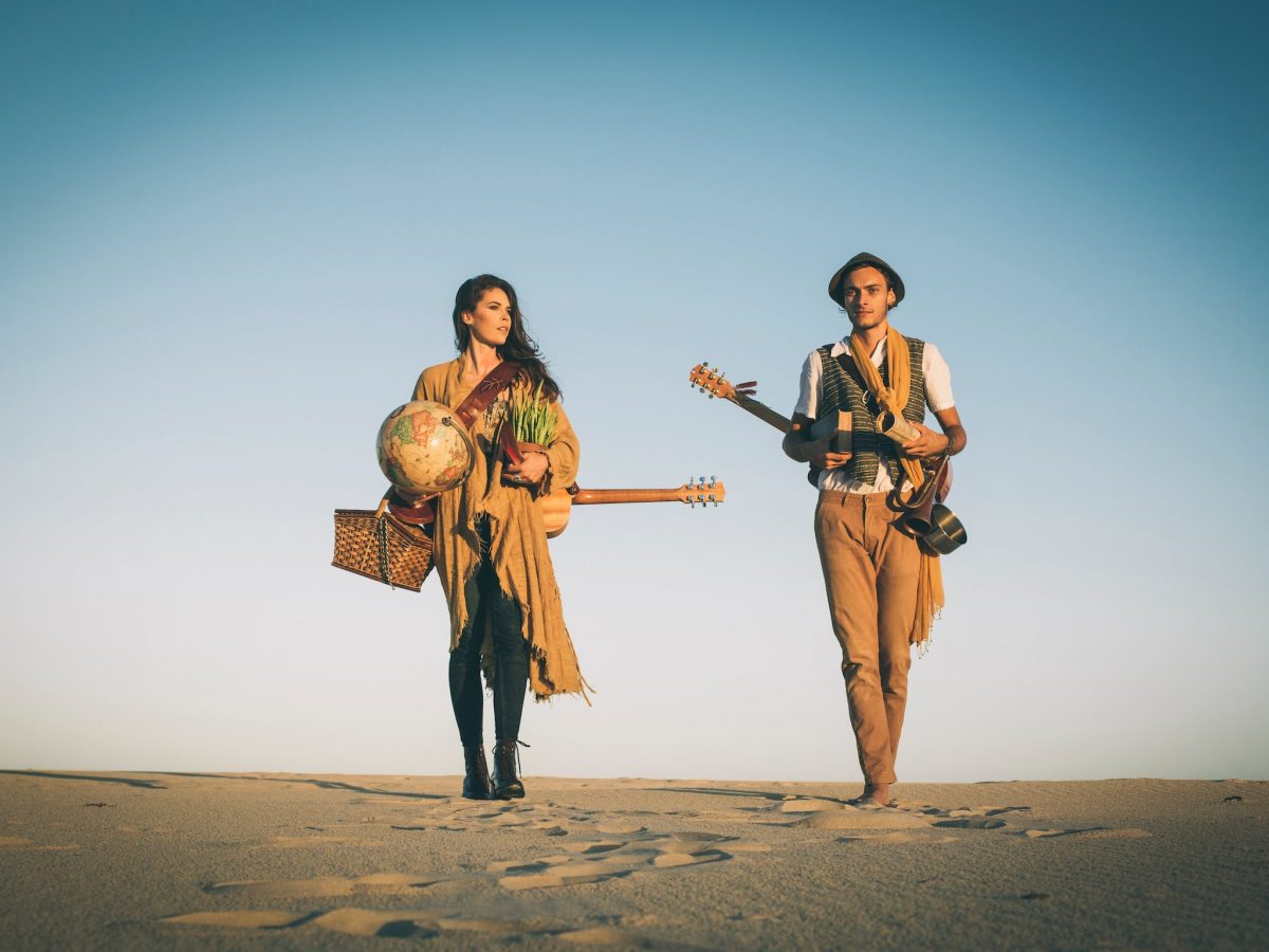 Two musicians from band Saije walking in the dessert with instruments
