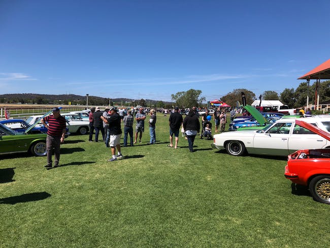 people milling around classic cars on a showground