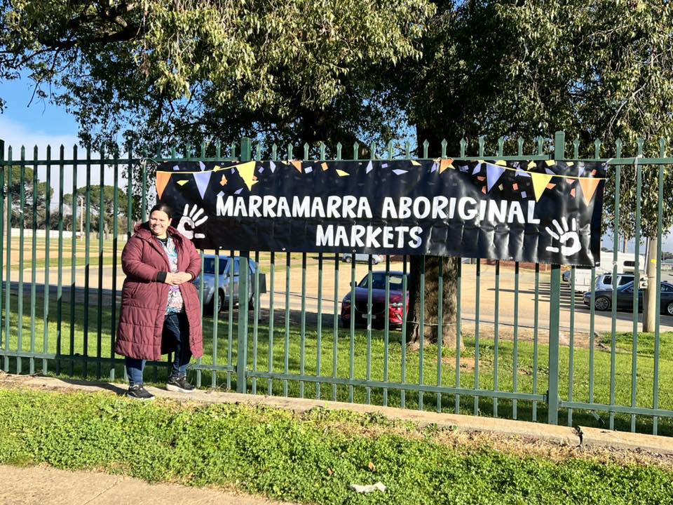 Woman standing in front of banner that reads Marramarra Aboriginal Markets