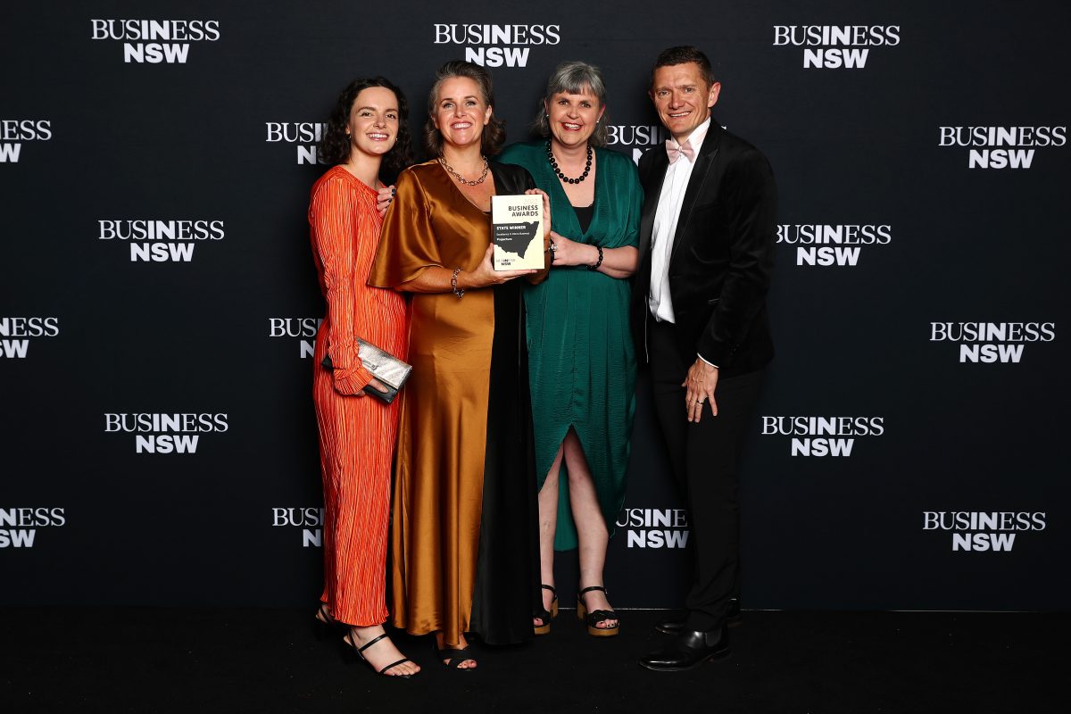 Three award winners pose with Business NSW director 