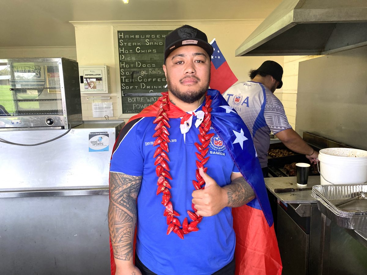 Michael Tomi drapped with the Samoan flag does the thumbs up