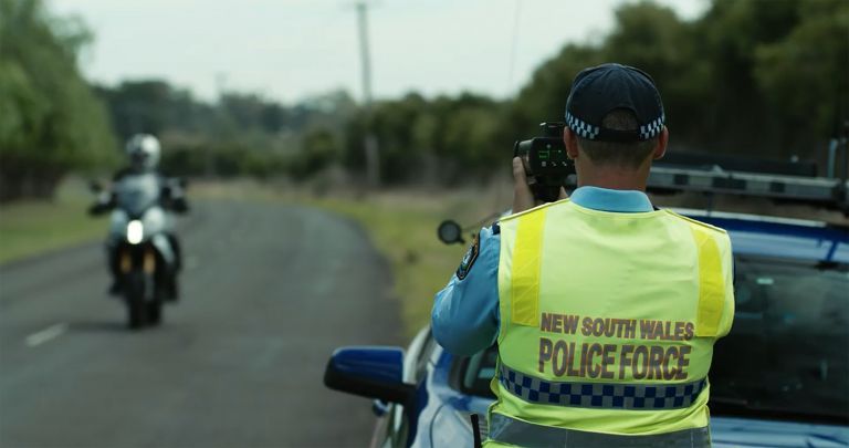 policeman aims radar at motorcyclist