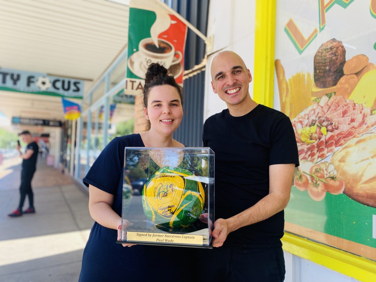Salvatore and his sister Maria Trimboli hold the Paul Wade signed ball outside his store.