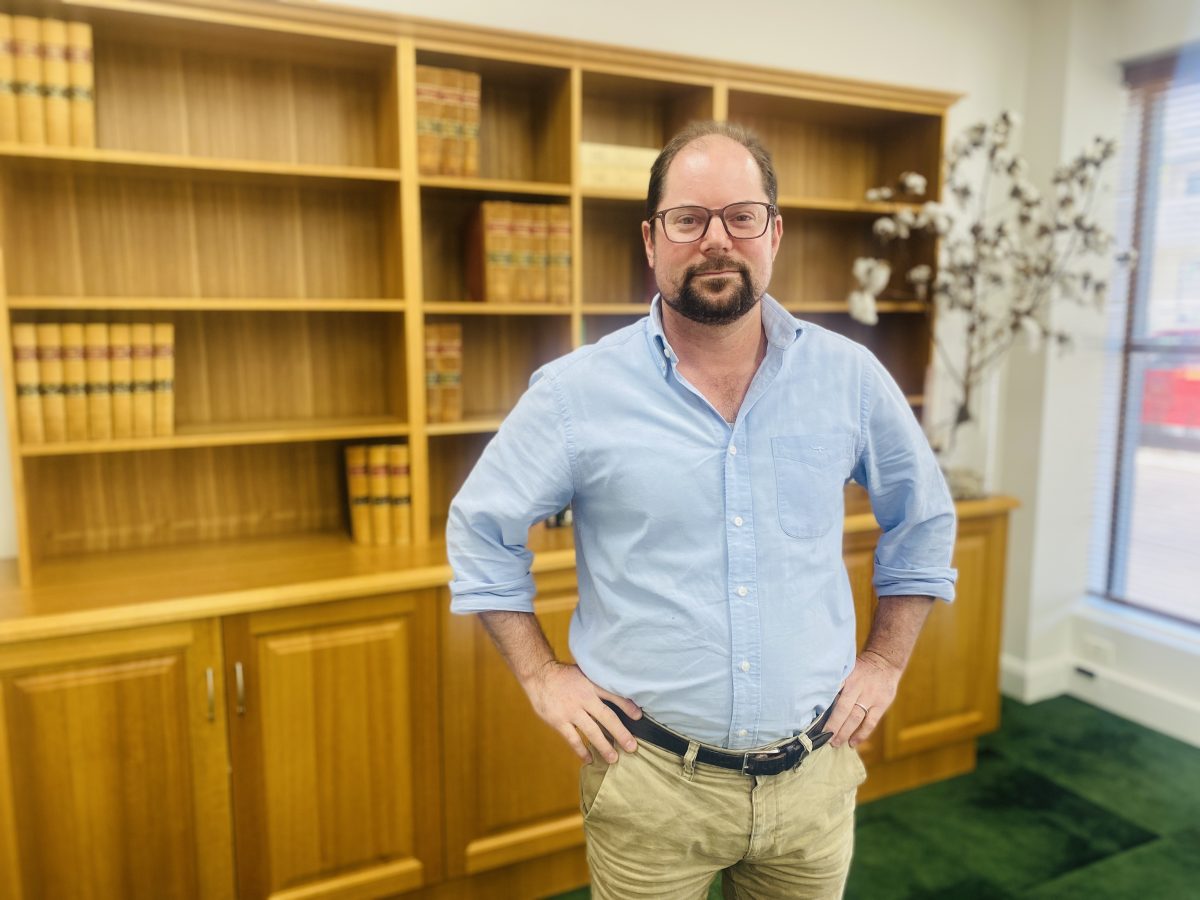 John Nikolic in front of a bookshelf