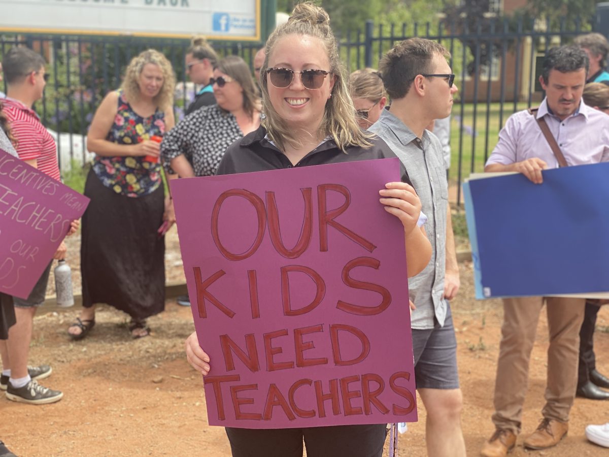 Woman stands with sign at teacher protest