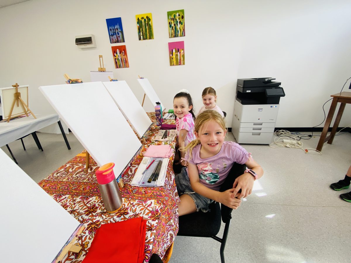 A row of three kids painting