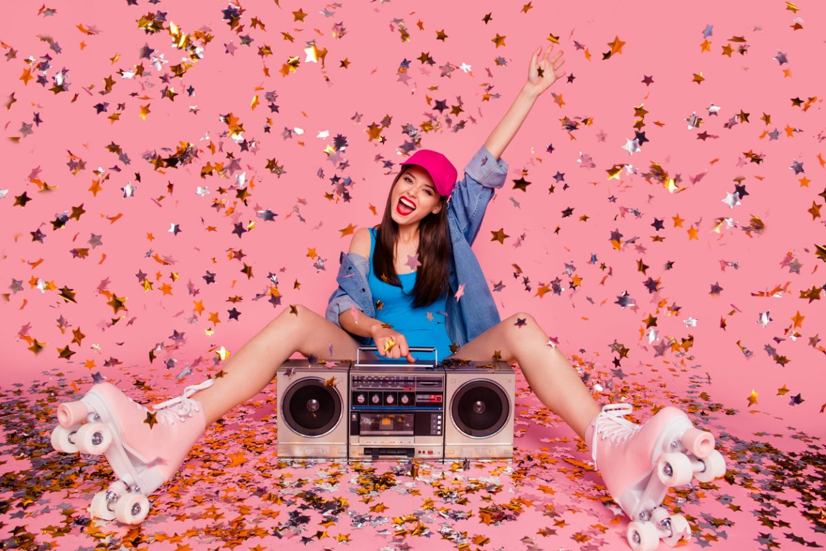 Woman sitting in rollerskates, holding a boombox