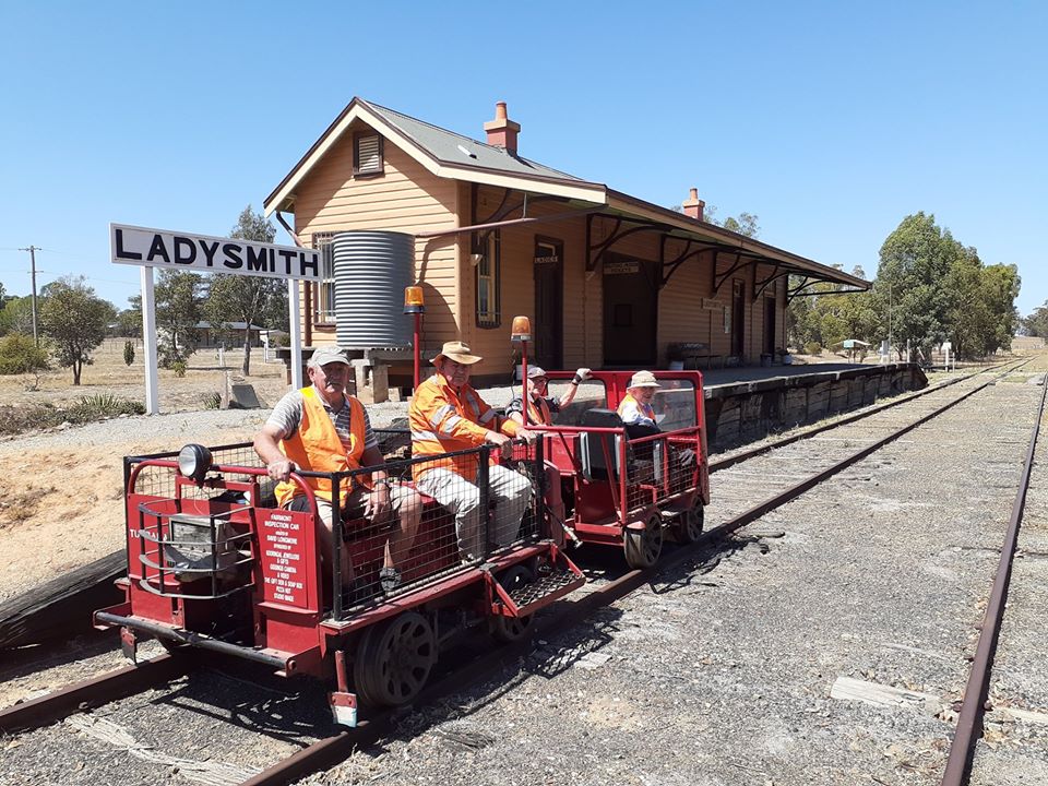 people sitting on a train carriage in front of a station