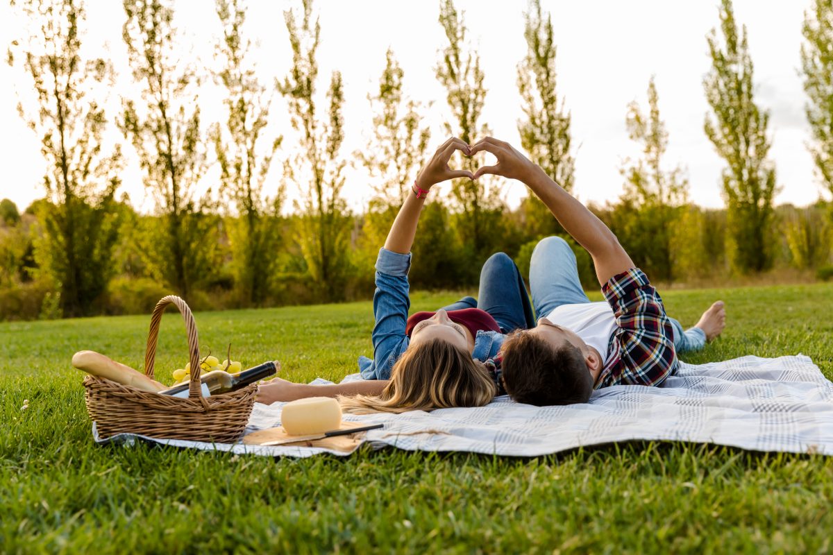 two people having a picnic making a heart shape with their hands