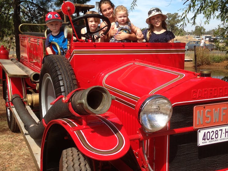 Family sitting in a red vintage car at the Temora Annual Live Exhibition