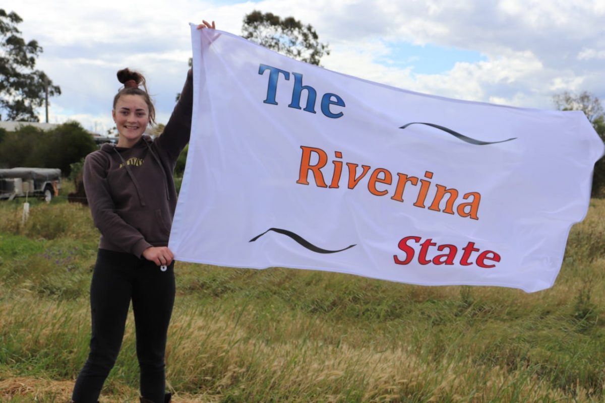 Photo of woman holding Riverina State banner