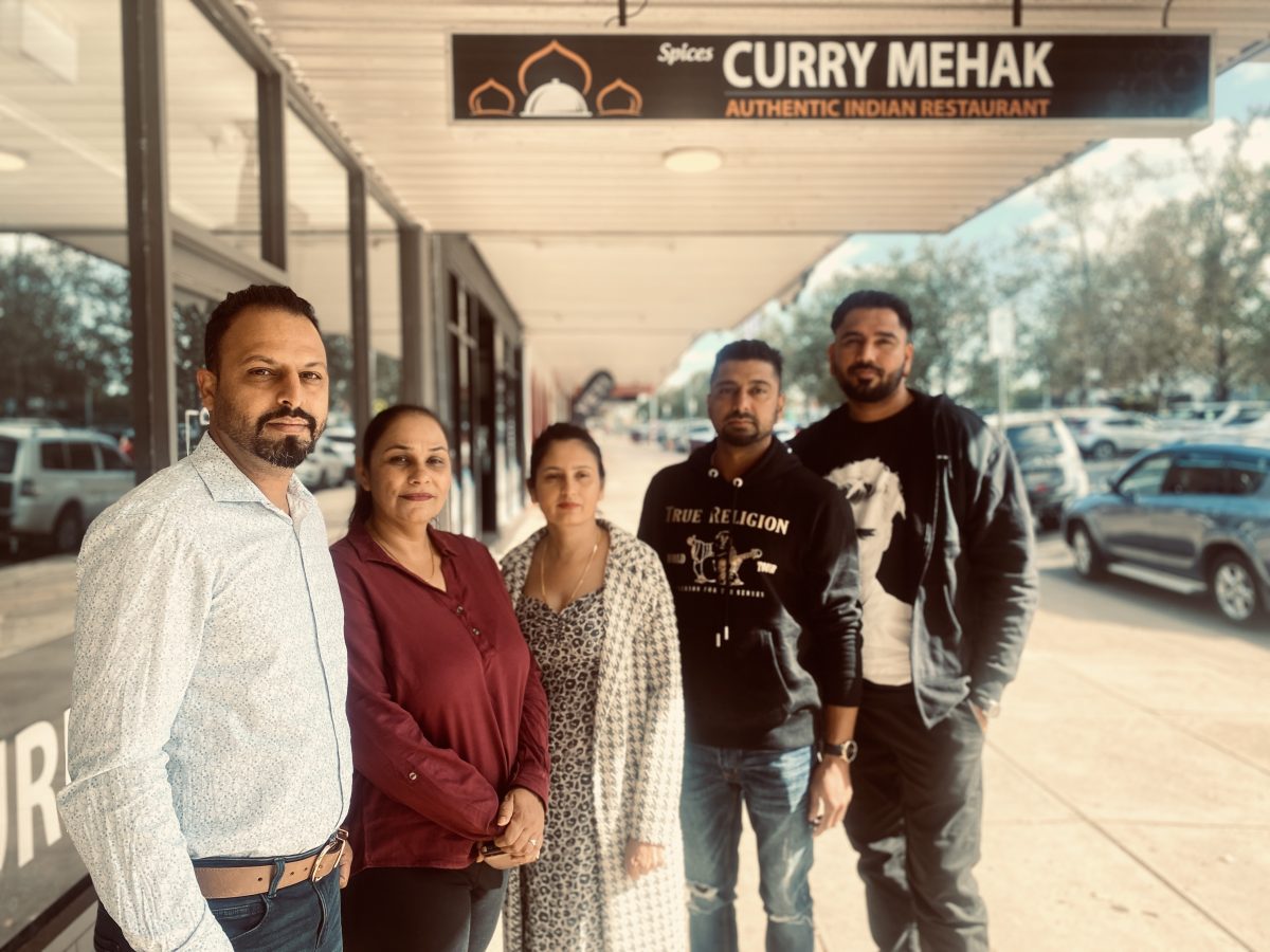 Singh family underneath restaurant sign 