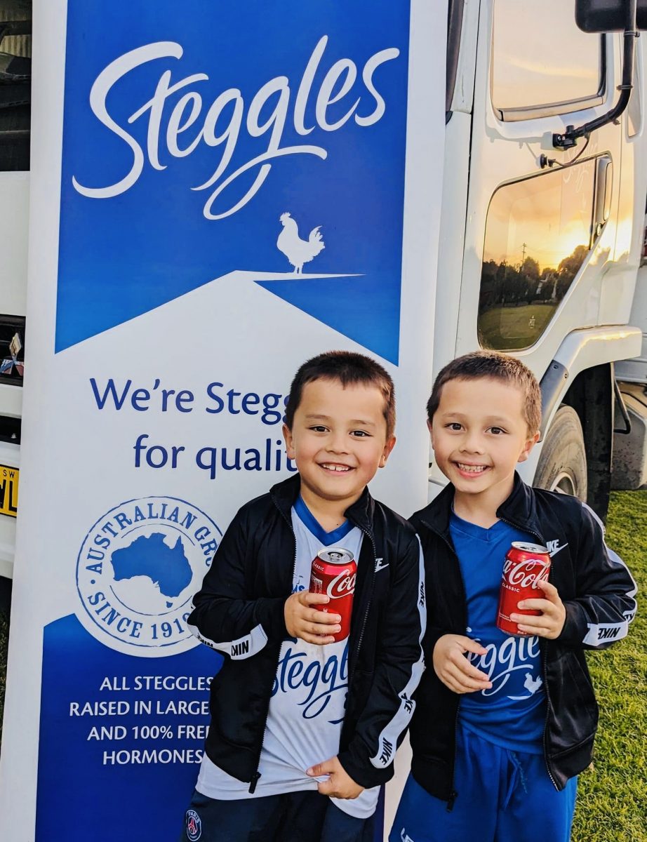 Two kids enjoying a drink at Steggles sign