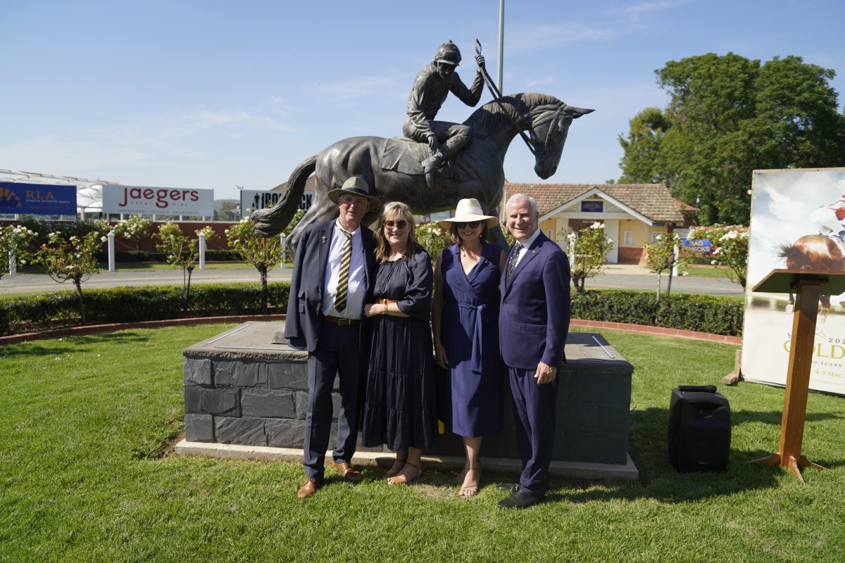 four people posing with a statue