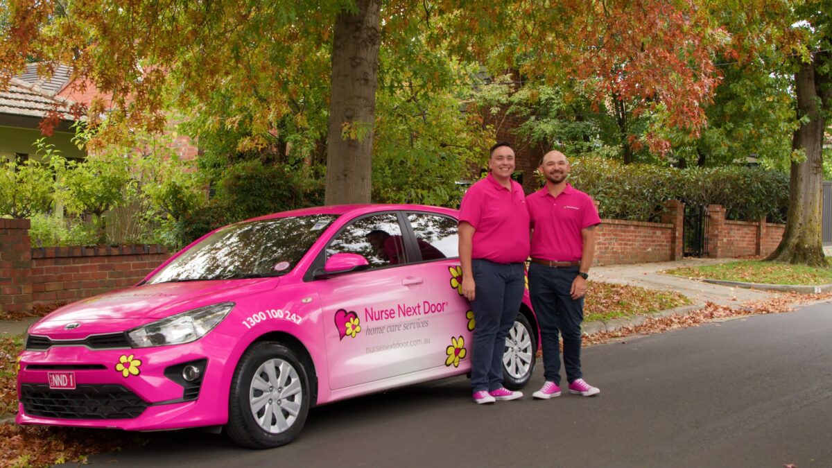 Two men next to a pink car
