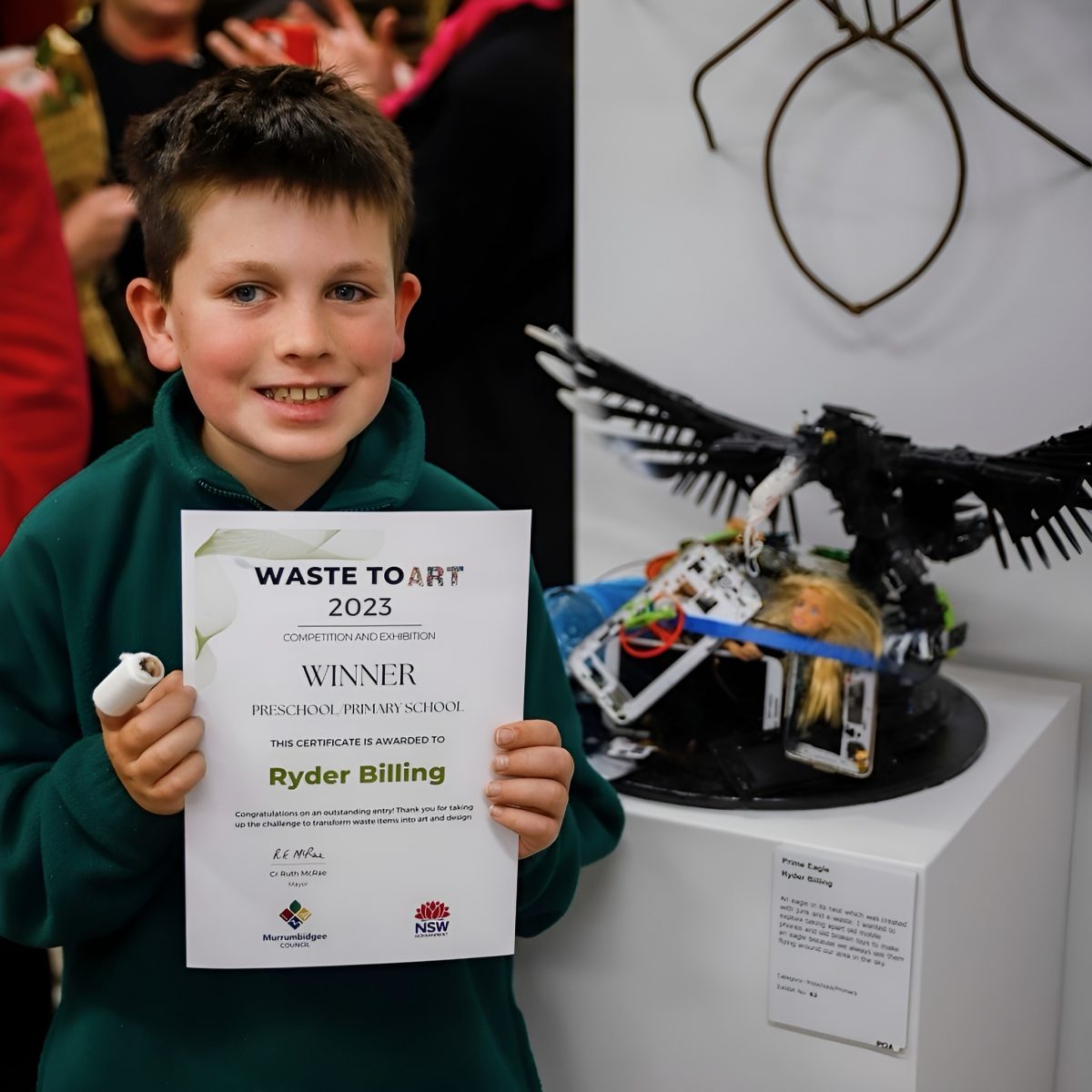 A boy with his art and award certificate