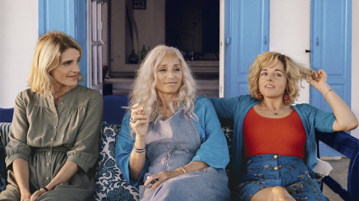 Still from Two Tickets to Greece showing Olivia Cote, Kristin Scott Thomas and Laure Calamy sitting on a chaise
