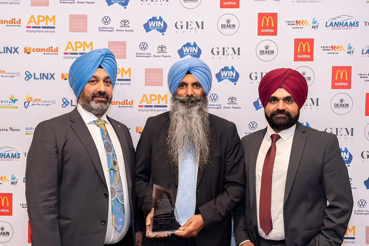 Three Sikhs in suits accept award
